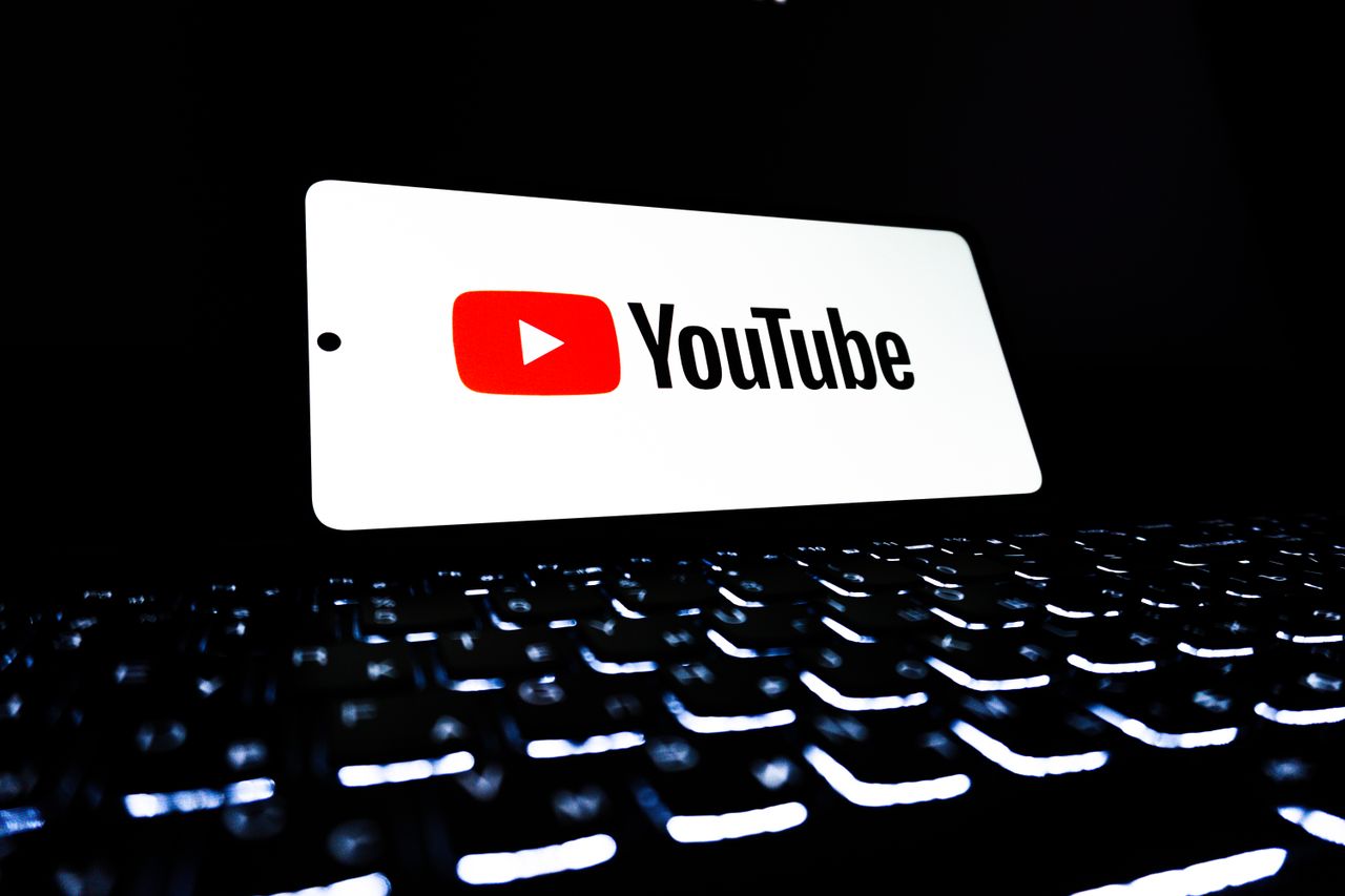 services-01 YouTube app icon displayed on a smartphone over an illuminated keyboard, representing digital media and online streaming.